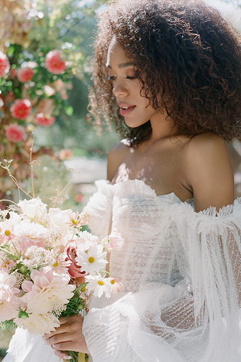  romantic wedding at colony 29 with the bride in a tulle ballgown with sleeves and the groom in a diamond black tuxedo – bride close up smelling the flowers  