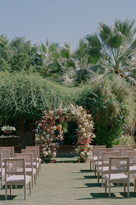  romantic wedding at colony 29 with the bride in a tulle ballgown with sleeves and the groom in a diamond black tuxedo – rose floral arch   