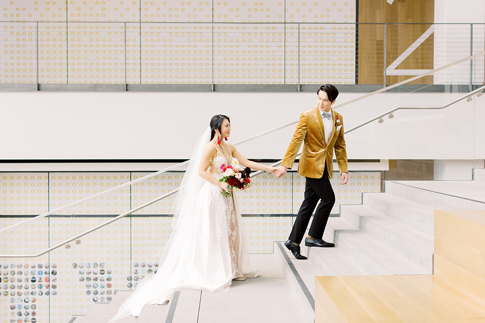  tropical and gold wedding with red accents – couple walking up the stairs 