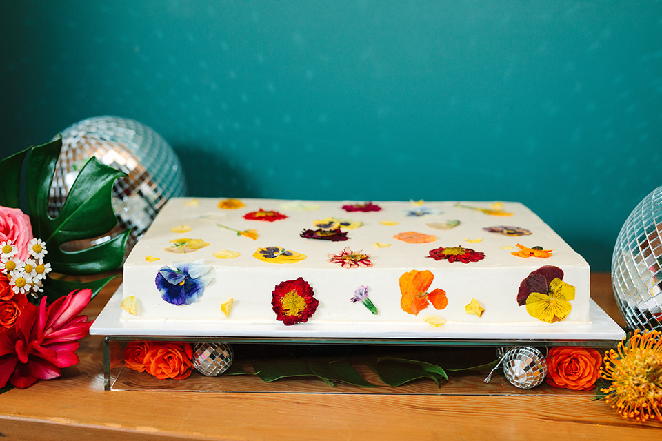  a colorful disco wedding in dtla with the bride in a champagne gown with metallic stars and the groom in a cobalt blue suit – floral sheet cake