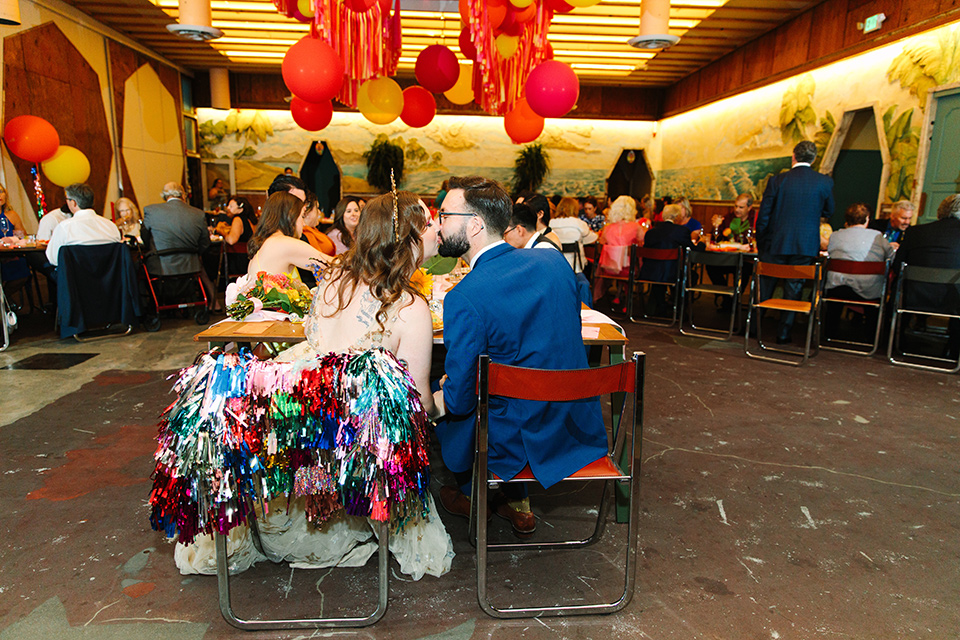  a colorful disco wedding in dtla with the bride in a champagne gown with metallic stars and the groom in a cobalt blue suit – couple at the sweetheart table