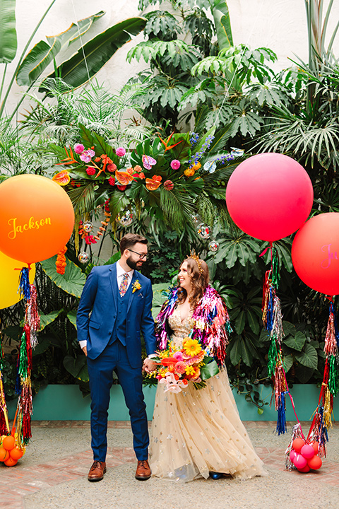  a colorful disco wedding in dtla with the bride in a champagne gown with metallic stars and the groom in a cobalt blue suit – couple with the balloons 
