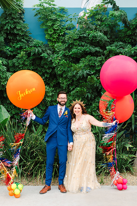  a colorful disco wedding in dtla with the bride in a champagne gown with metallic stars and the groom in a cobalt blue suit – couple with balloons 