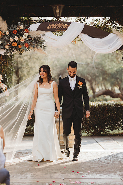  a fall toned wedding at the Fallbrook Estate Wedgewood venue with the groom and groomsmen in grey suits and the bridesmaids in orange – first kiss and the ceremony 