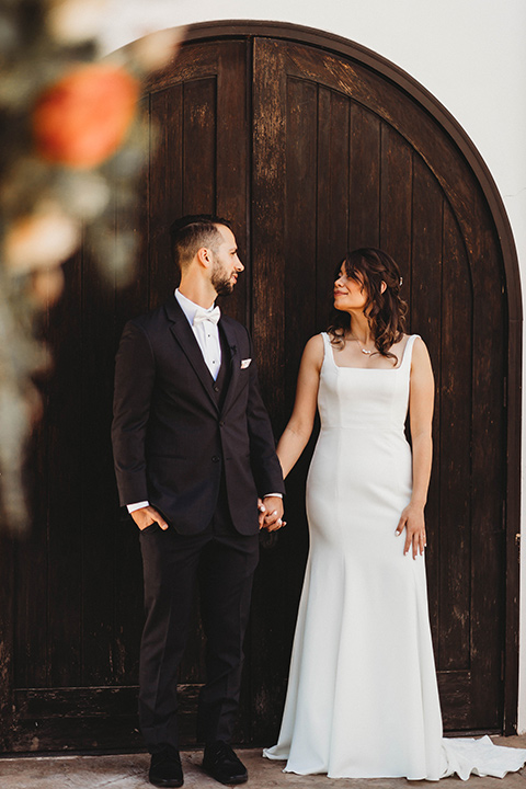  a fall toned wedding at the Fallbrook Estate Wedgewood venue with the groom and groomsmen in grey suits and the bridesmaids in orange – couple standing by the iron door