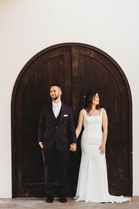  a fall toned wedding at the Fallbrook Estate Wedgewood venue with the groom and groomsmen in grey suits and the bridesmaids in orange – couple standing by the iron door