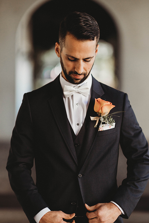  a fall toned wedding at the Fallbrook Estate Wedgewood venue with the groom and groomsmen in grey suits and the bridesmaids in orange – groom looking down