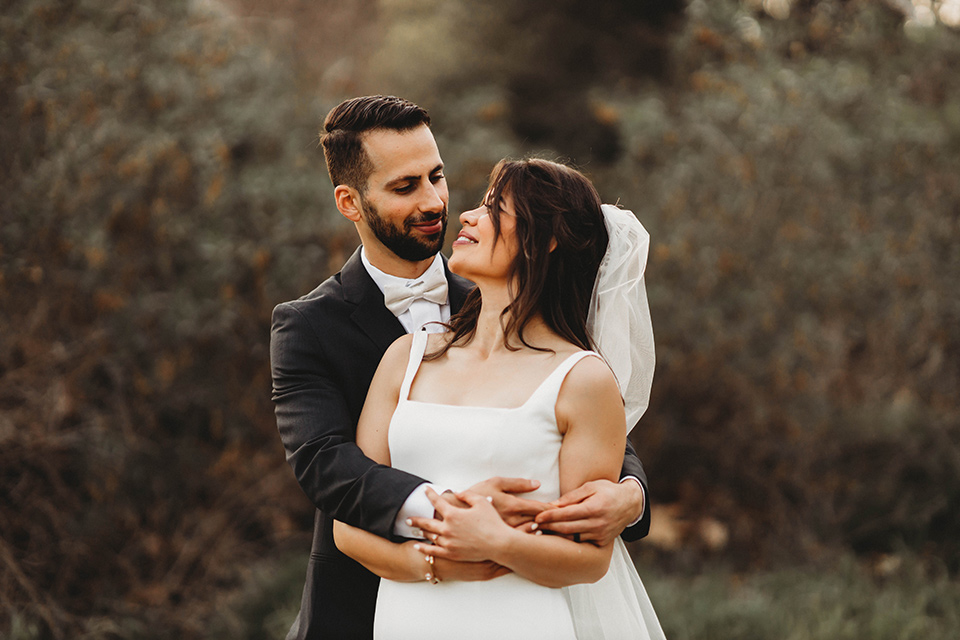  a fall toned wedding at the Fallbrook Estate Wedgewood venue with the groom and groomsmen in grey suits and the bridesmaids in orange – couple embracing 