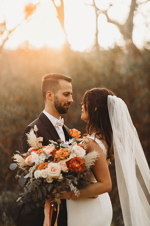  a fall toned wedding at the Fallbrook Estate Wedgewood venue with the groom and groomsmen in grey suits and the bridesmaids in orange – couple walking outside
