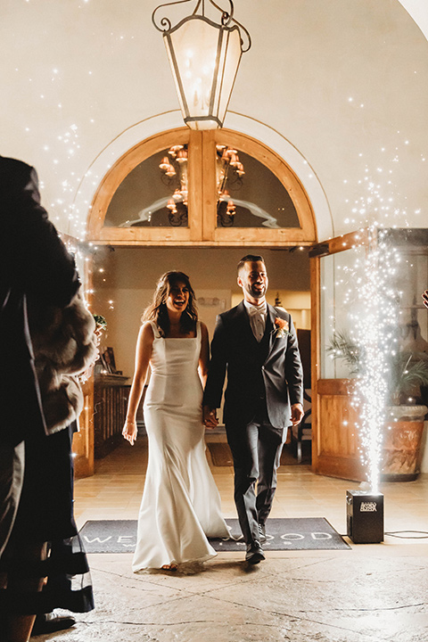  a fall toned wedding at the Fallbrook Estate Wedgewood venue with the groom and groomsmen in grey suits and the bridesmaids in orange – couple walking into the reception with sparklers