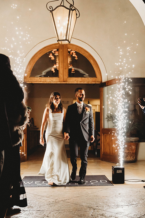  a fall toned wedding at the Fallbrook Estate Wedgewood venue with the groom and groomsmen in grey suits and the bridesmaids in orange – couple walking into the reception with sparklers 