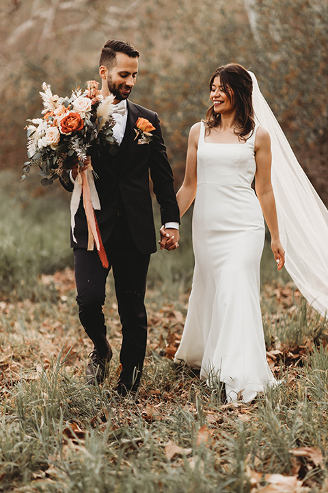  a fall toned wedding at the Fallbrook Estate Wedgewood venue with the groom and groomsmen in grey suits and the bridesmaids in orange – couple walking