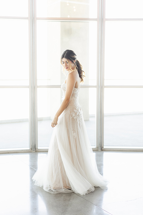 Modern romantic city wedding with an all-white color scheme and bright florals – one bride wore a strapless a-line gown and the other bride wore a white suit – bride walking away from camera in her wedding gown 