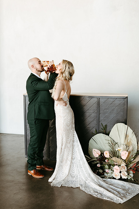  tropical metallic wedding with the bride in an ivory lace gown and the groom in a green suit 