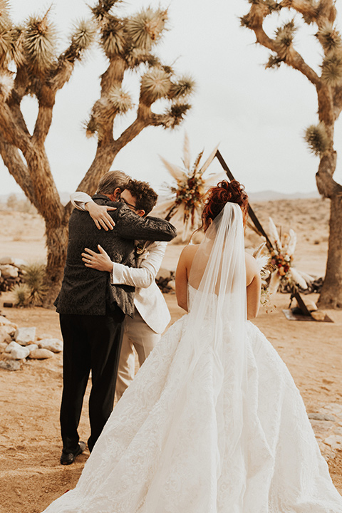  Jillian Rose Reed’s fabulous desert boho wedding – bride in a white ball gown and the groom hugging the father of the bride