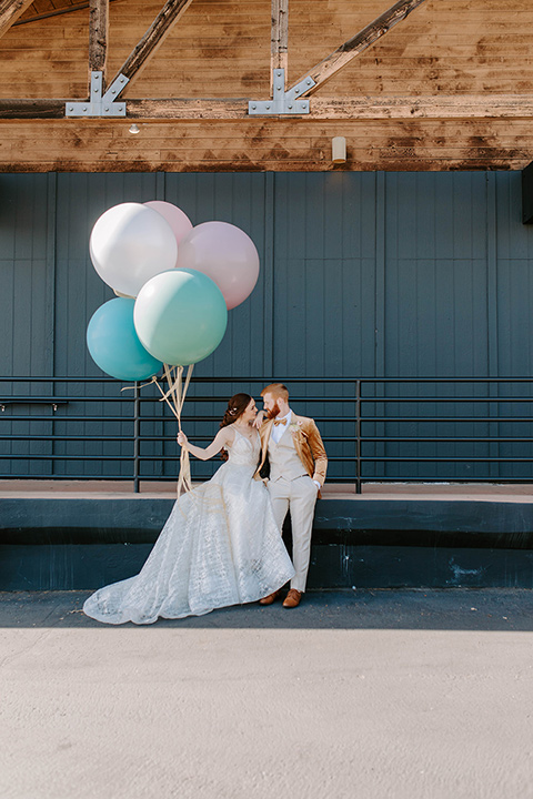  pastel and gold wedding with celestial décor – and the groom in a tan suit and a gold velvet tuxedo – couple with balloons 