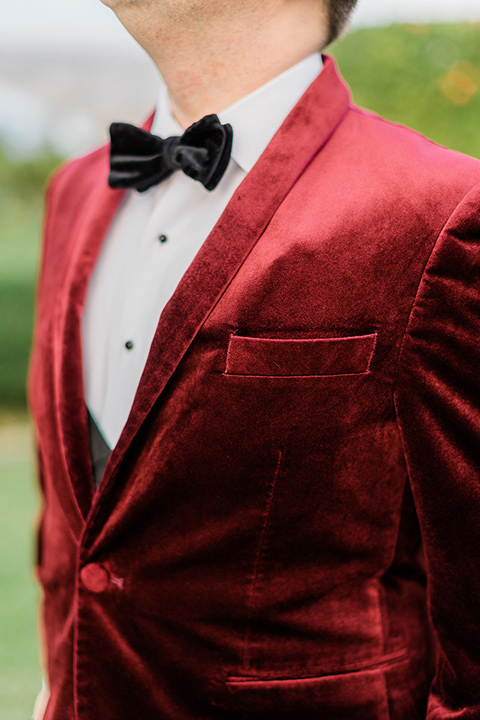  romantic winter inspired wedding theme with luxe textures and details, one groom wore a burgundy velvet shawl tuxedo and the other groom in a black paisley tuxedo – groom in a burgundy velvet tuxedo 