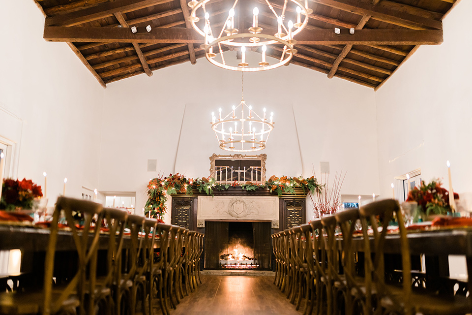  romantic winter inspired wedding theme with luxe textures and details, one groom wore a burgundy velvet shawl tuxedo and the other groom in a black paisley tuxedo – reception space with a lodge style feel to it and winter decor