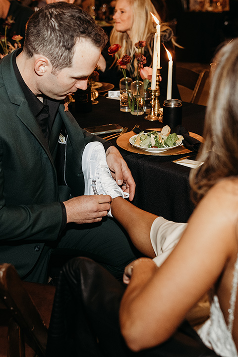  boho autumn wedding with the groom and groomsmen in a green suit – bride putting on tennis shoes