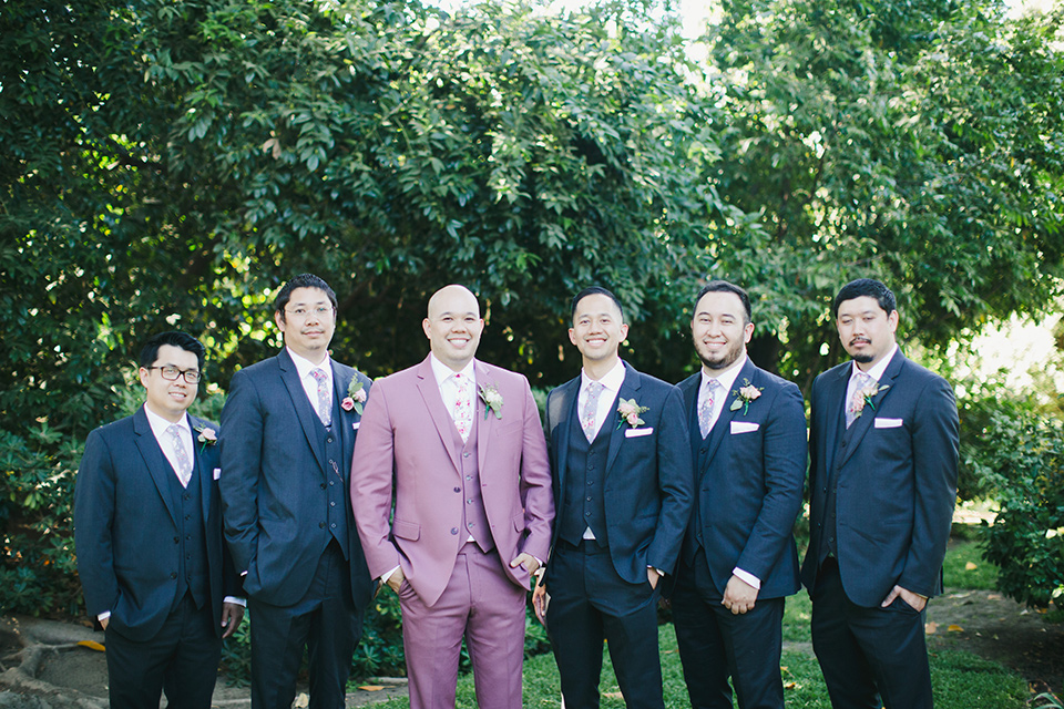  garden wedding at rancho los Cerritos with the groom in a rose pink suit and the groomsmen in navy suits 