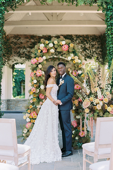  old world garden wedding design with yellow and pink flowers and the groom in a navy shawl tuxedo – ceremony arch 