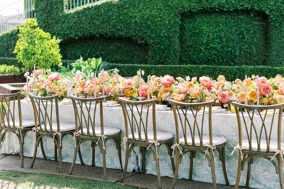  old world garden wedding design with yellow and pink flowers and the groom in a navy shawl tuxedo