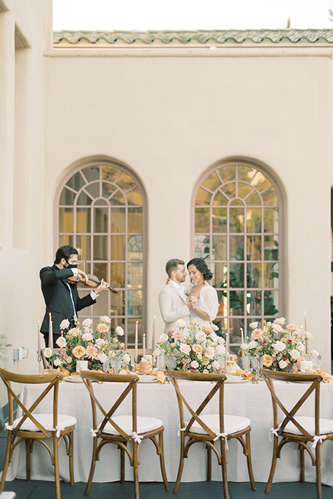  a neutral romantic wedding with touches of peach colors and the groom in a tan suit- at the table 