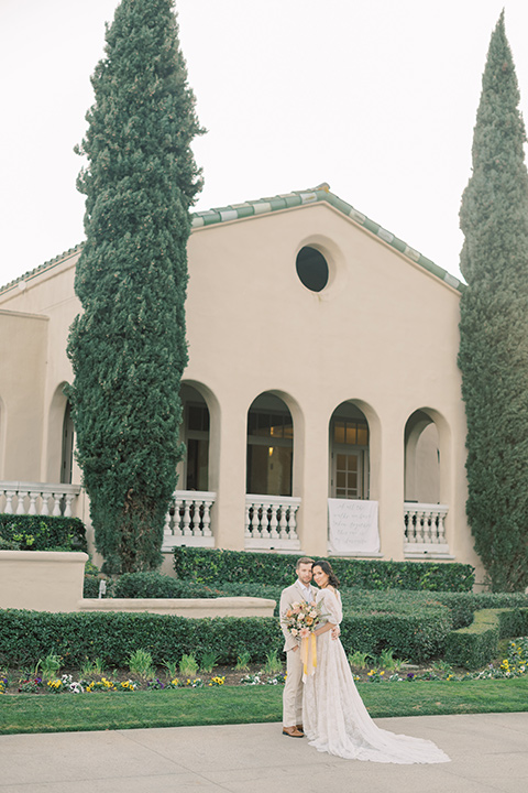  a neutral romantic wedding with touches of peach colors and the groom in a tan suit- at the venue 