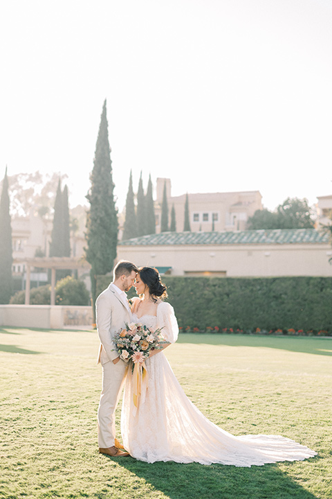  a neutral romantic wedding with touches of peach colors and the groom in a tan suit- bride 