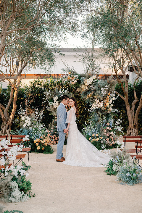 a wedding at the grand gimeno with white, blue, and gold accents – the bride wore a long sleeved modern fitted gown and the groom wore a light blue suit with velvet bow tie – bride and groom at a ceremony