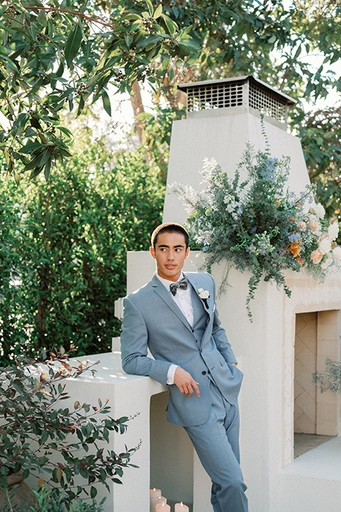 a wedding at the grand gimeno with white, blue, and gold accents – the bride wore a long sleeved modern fitted gown and the groom wore a light blue suit with velvet bow tie – groom standing outside