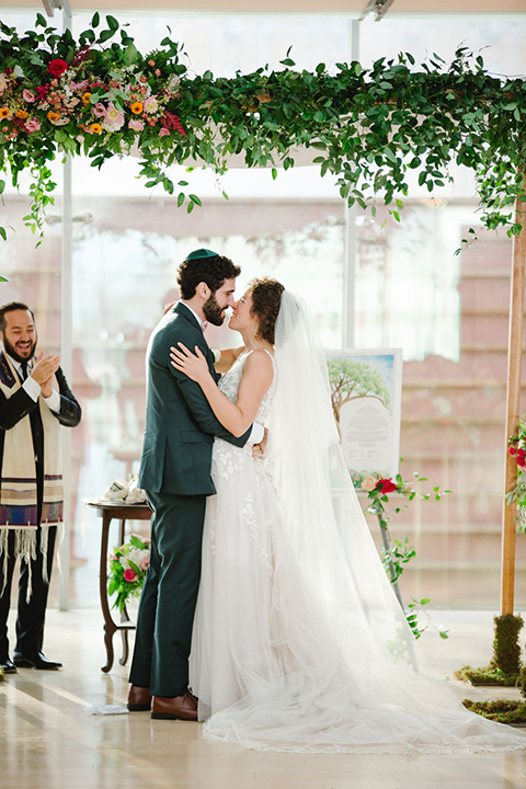  a downtown wedding at the cultural center with the groom and groomsmen in green suits and the bridesmaids in blush dresses and the bride in an a-line gown- first kiss