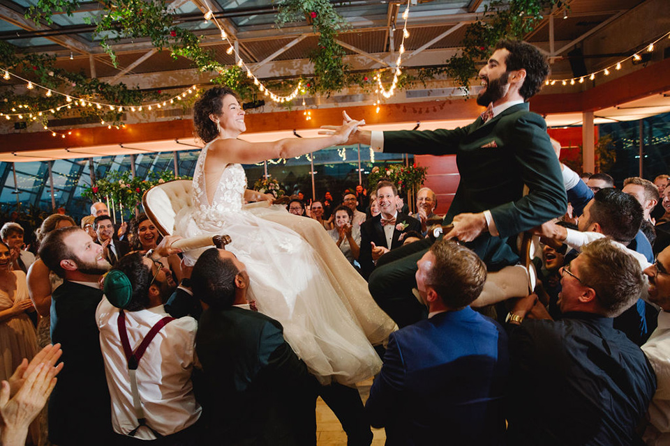  a downtown wedding at the cultural center with the groom and groomsmen in green suits and the bridesmaids in blush dresses and the bride in an a-line gown- couple being lifted in chairs