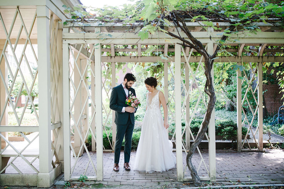  a downtown wedding at the cultural center with the groom and groomsmen in green suits and the bridesmaids in blush dresses and the bride in an a-line gown- couple looking at the flowers at the wedding