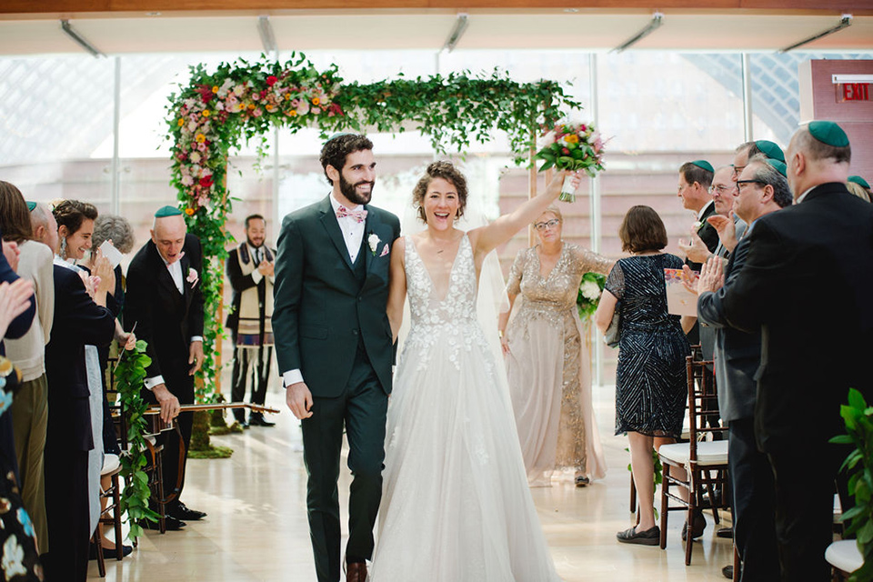  a downtown wedding at the cultural center with the groom and groomsmen in green suits and the bridesmaids in blush dresses and the bride in an a-line gown- couple walking down the aisle as husband and wife