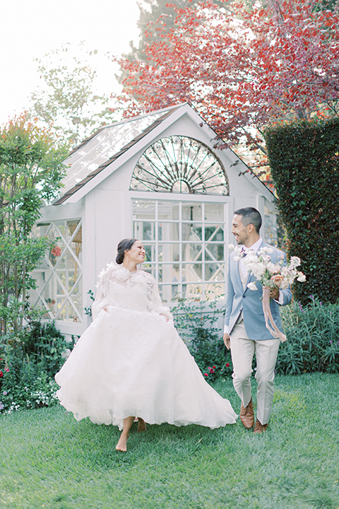  A French inspired wedding at a lavender farm with the bride in a fashion-forward white a-line gown with a high neckline and three dimensional floral appliques on it, the groom wore a light blue suit coat with a pair of tan pant and a grey velvet bow tie, couple at the ceremony