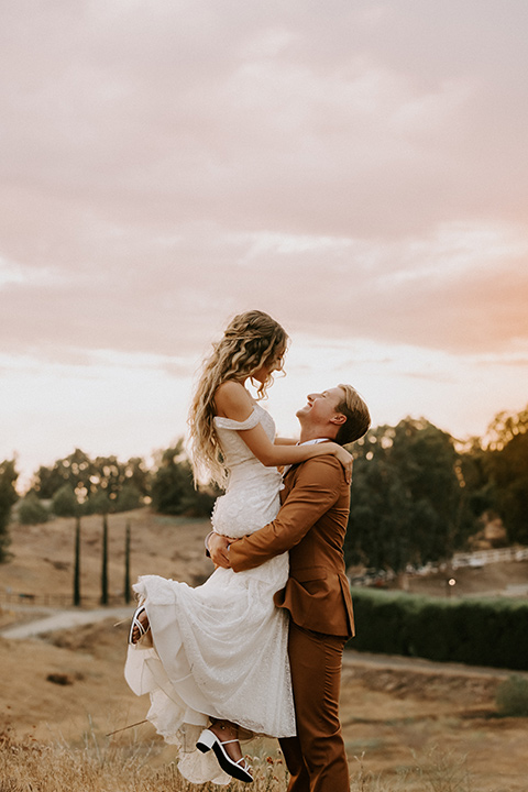  rustic boho wedding with warm colors and the bride in an off the shoulder gown and the groom in a caramel suit 