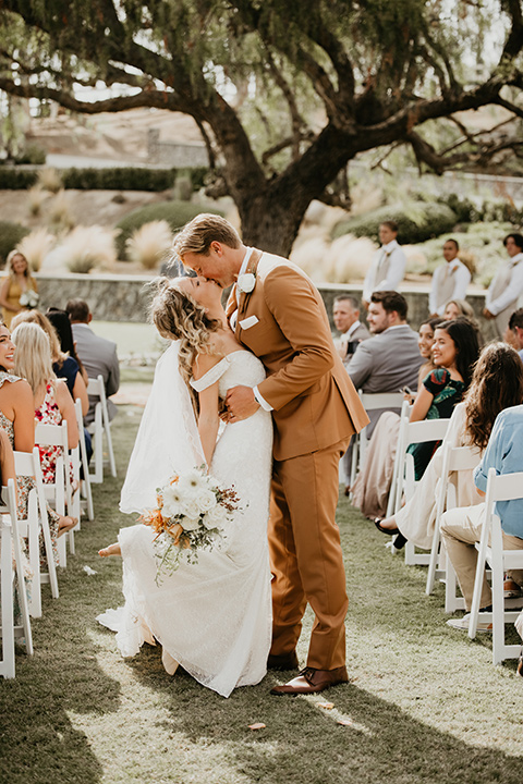  rustic boho wedding with warm colors and the bride in an off the shoulder gown and the groom in a caramel suit 