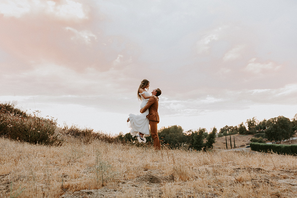  rustic boho wedding with warm colors and the bride in an off the shoulder gown and the groom in a caramel suit 