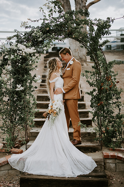  rustic boho wedding with warm colors and the bride in an off the shoulder gown and the groom in a caramel suit 