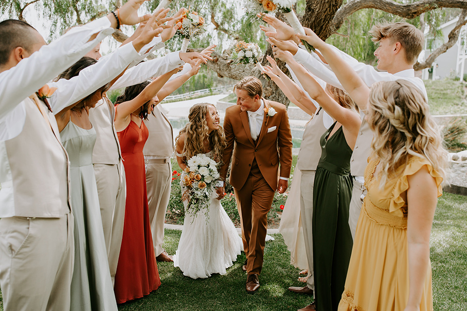  rustic boho wedding with warm colors and the bride in an off the shoulder gown and the groom in a caramel suit 