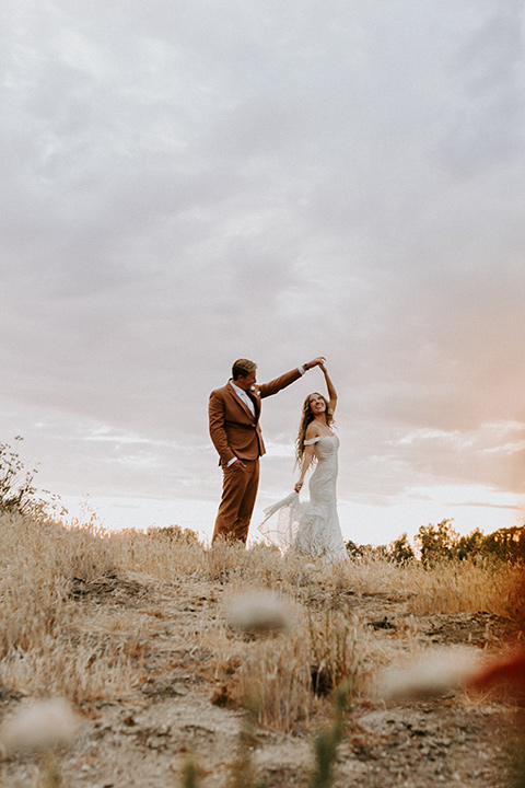  rustic boho wedding with warm colors and the bride in an off the shoulder gown and the groom in a caramel suit 