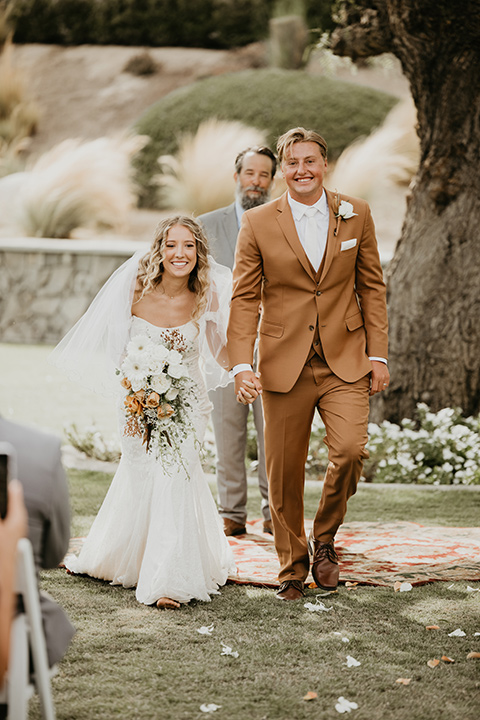  rustic boho wedding with warm colors and the bride in an off the shoulder gown and the groom in a caramel suit 