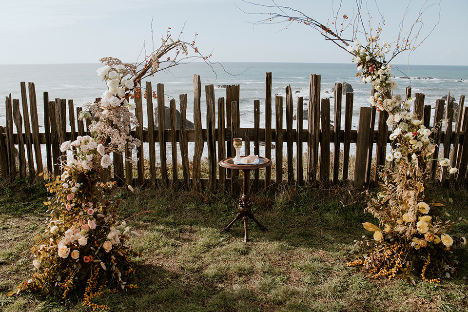  lizzie and tommys wedding on the beach with neutral colors and a gold velvet jacket - arch