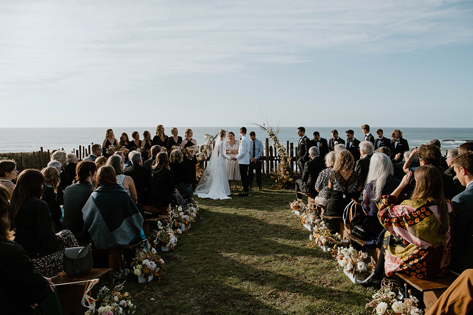  lizzie and tommys wedding on the beach with neutral colors and a gold velvet jacket – ceremony