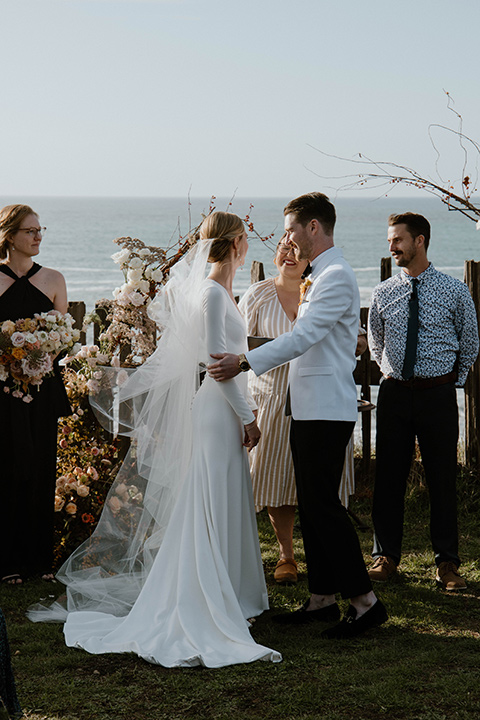  lizzie and tommys wedding on the beach with neutral colors and a gold velvet jacket – ceremony 