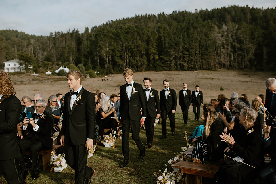  lizzie and tommys wedding on the beach with neutral colors and a gold velvet jacket – groomsmen walking down the aisle