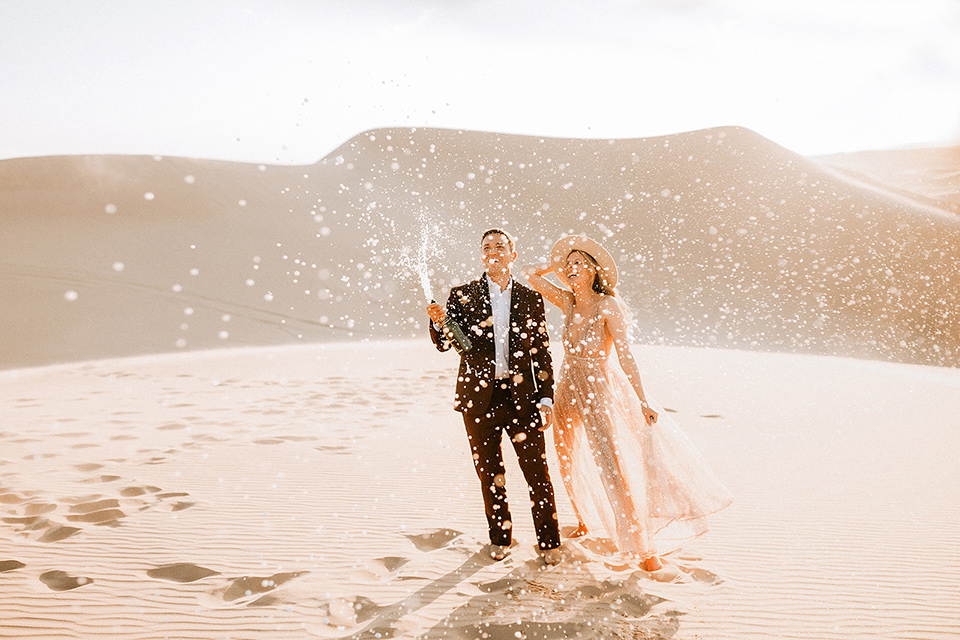  image of a couple at their engagement shoot celebrating with spraying champagne everywhere