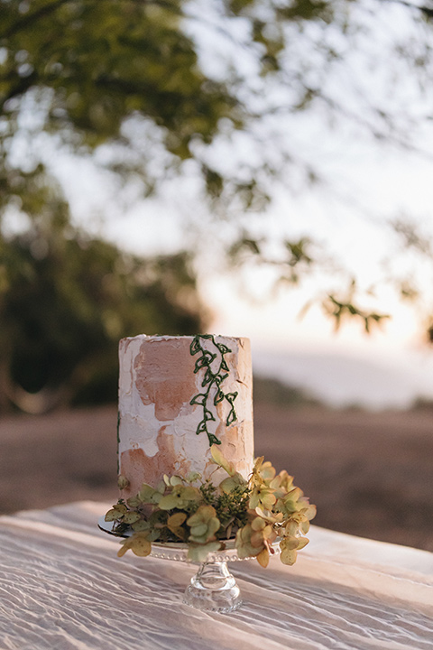  an elevated cottagecore wedding design in a barn venue with gold and tan tones – the bride in a white gown with long sleeves and the groom in a tan suit – cake 