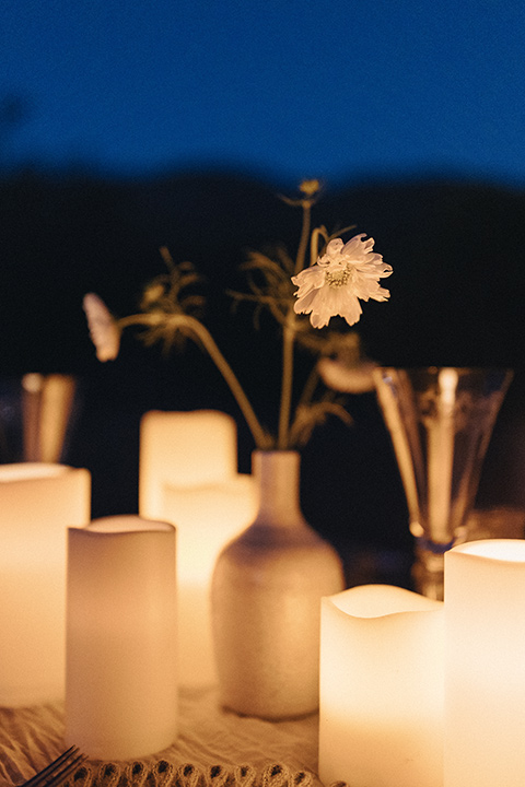  an elevated cottagecore wedding design in a barn venue with gold and tan tones – the bride in a white gown with long sleeves and the groom in a tan suit – candles 